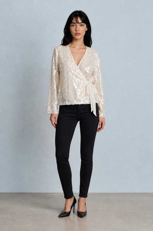 Woman wearing a white sequin top and black pants against a light gray background